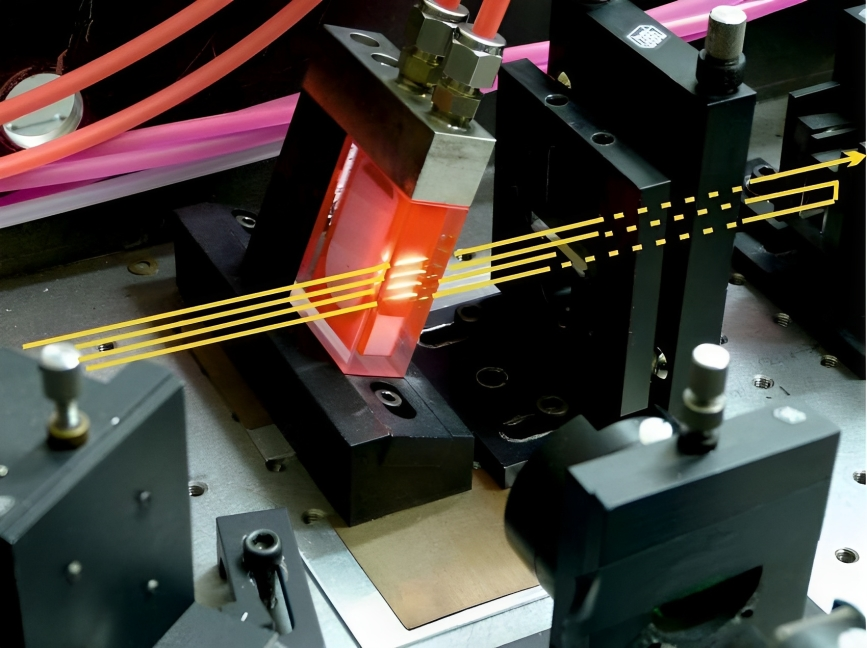 Close-up photo of a dye laser cell showing tubes, the dye cell, and circulation of the dye. Optical beam paths are highlighted with overlaid lines.