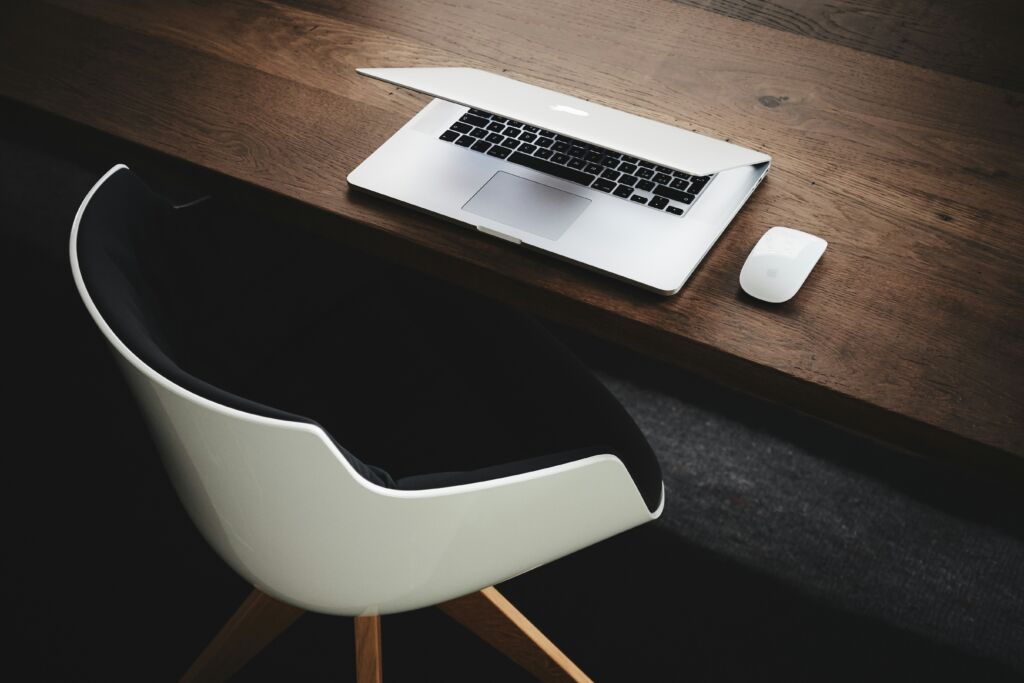 A minimalist workspace with an open laptop and a mouse on a clean desk, symbolizing organized sales habits.